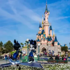 Myszka Miki i Minnie przed zamkiem w Disneylandzie. Sprawdź aktualną disneyland cena biletu, by zaplanować magiczną podróż!
