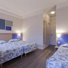 Pokój z trzema łóżkami w hotelu, idealny na paryż tanie noclegi u sióstr. Wygodne łóżka z niebiesko-białą pościelą.