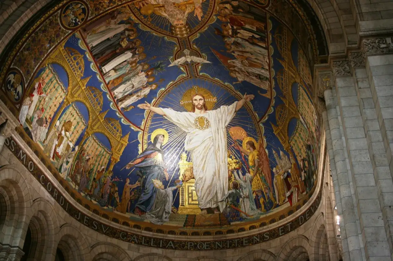Witraż w bazylice Sacré-Cœur przedstawia Chrystusa w otoczeniu świętych i aniołów, symbolizując jego triumf i miłosierdzie.