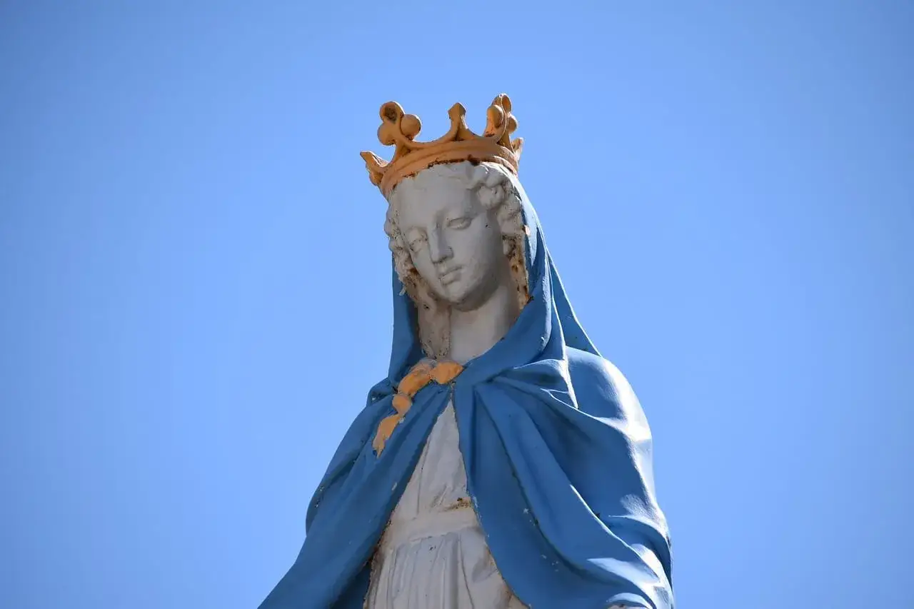 Posąg Matki Boskiej w koronie, symbol francuskiego ośrodka kultu maryjnego, na tle błękitnego nieba.