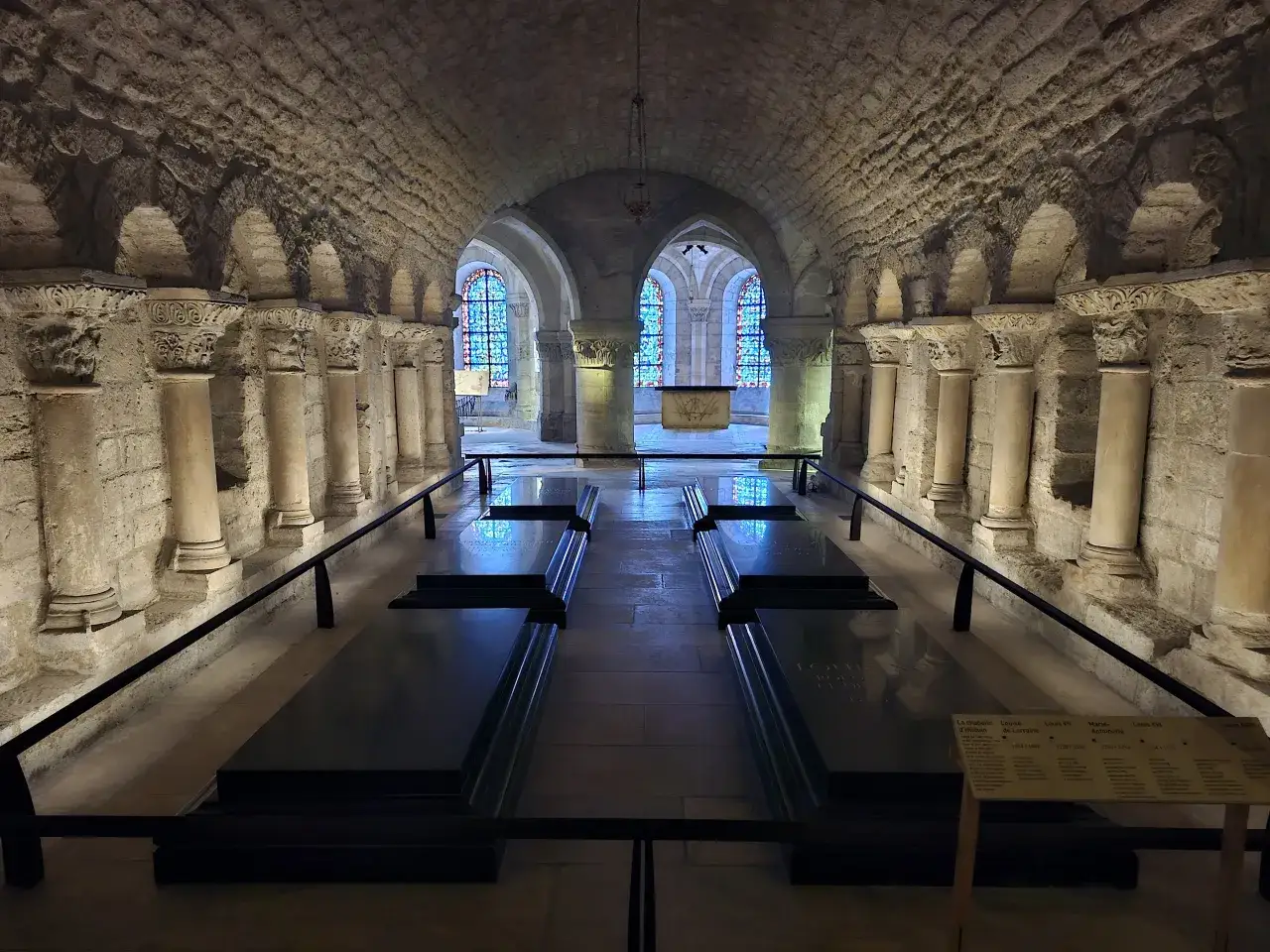 Grobowce królewskie w bazylice Saint-Denis. Kamienne kolumny i łuki tworzą sklepienie nad sarkofagami.