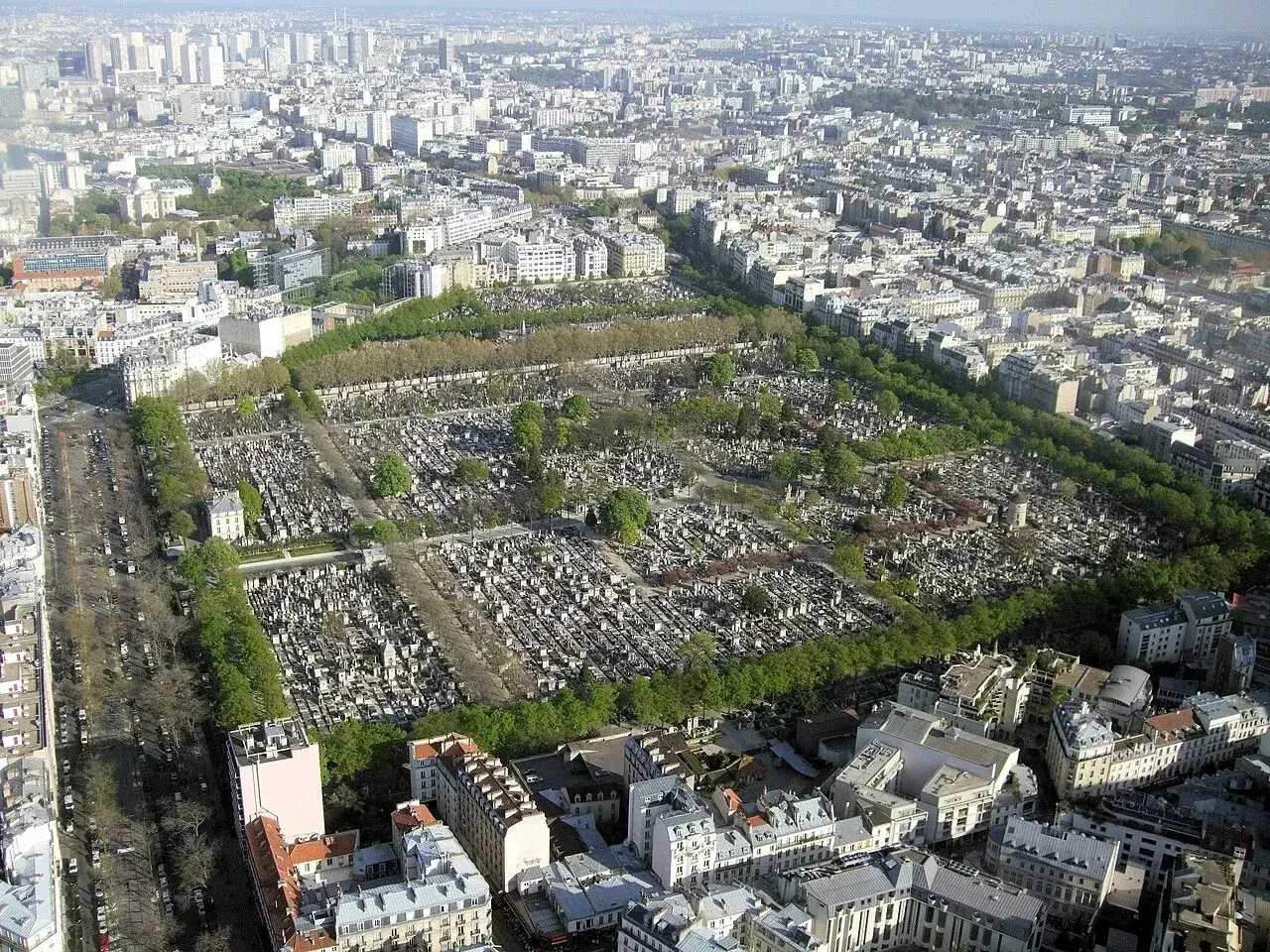 Widok z lotu ptaka na cmentarz Montparnasse, część 14 dzielnicy Paryża, otoczony zielenią i miejską zabudową.